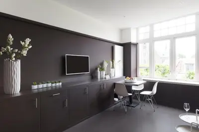 a kitchen with a black wall with a table and a tv at 2L Hof van Holland apartments in Noordwijk