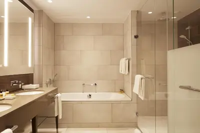 a bathroom with a tub and two sinks and a shower at Hyatt Regency Amsterdam in Amsterdam
