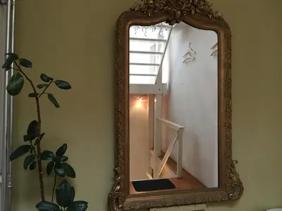 an ornate mirror in a room with a window at La Perle Apartment in Utrecht