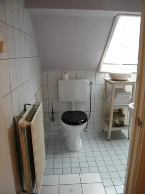 a bathroom with a toilet with a black seat at La Perle Apartment in Utrecht