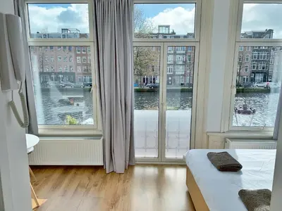 a bedroom with large windows with a view of the water at Jordaan View in Amsterdam