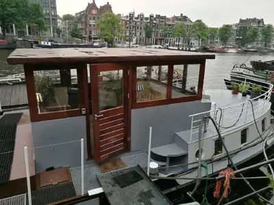 a boat docked at a dock in the water at houseboat Rose in Amsterdam
