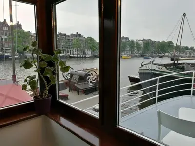 a window with a view of a boat in the water at houseboat Rose in Amsterdam