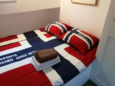 a bed with a red white and blue blanket and pillows at houseboat Rose in Amsterdam