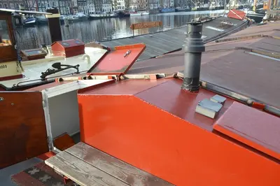 an orange boat on the water next to a river at houseboat Rose in Amsterdam