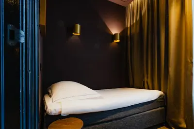 a small bed with white sheets in a room at De Jonker Urban Suites in Amsterdam