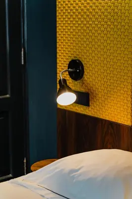 a lamp on a yellow wall next to a bed at De Jonker Urban Suites in Amsterdam