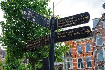 a street sign with street signs on a pole at De Jonker Urban Suites in Amsterdam