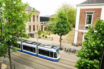 a blue and white train on a city street at De Jonker Urban Suites in Amsterdam