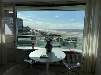 a table and chairs in front of a window with a view of the beach at Seaview 15 in Zandvoort