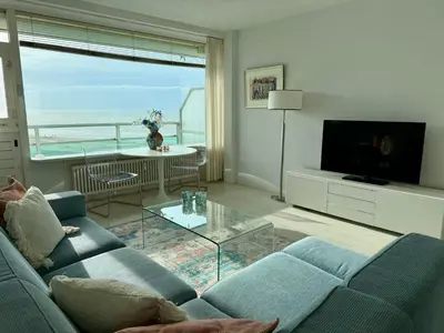 a living room with a blue couch and a view of the ocean at Seaview 15 in Zandvoort