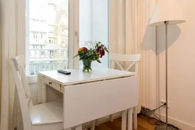 a white desk with a vase of flowers and a window at Old / New Pijp in Amsterdam