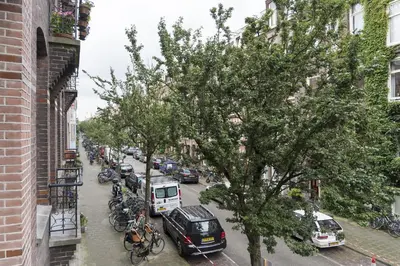 a city street with cars and bikes parked next to a building at Old / New Pijp in Amsterdam
