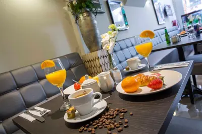 a table with two plates of food and two glasses of orange juice at Royal Plaza Hotel Amsterdam in Amsterdam