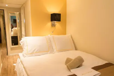 a bedroom with a white bed with a tv on the wall at Royal Plaza Hotel Amsterdam in Amsterdam