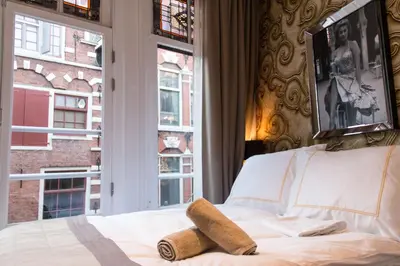 a bedroom with a bed and two windows at Royal Plaza Hotel Amsterdam in Amsterdam