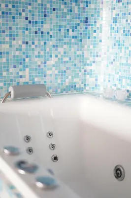 a white bath tub with a blue tiled wall at Vitamine Zee in IJmuiden