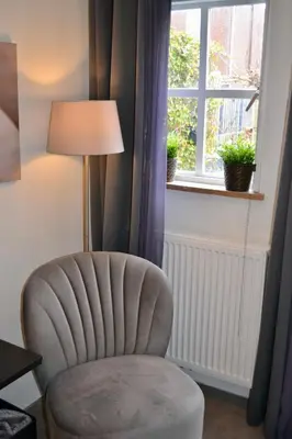 a chair in a room with a lamp and a window at Studio@25 in Zandvoort