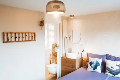 a bedroom with a bed and a bathroom with a sink at Villa La Vida in Egmond aan Zee