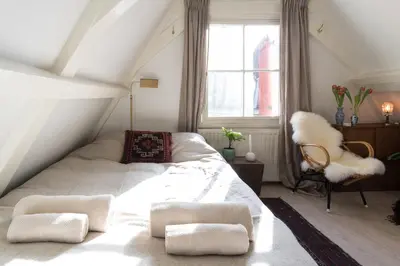 a bedroom with a white bed and a chair at Rembrandt Studio's in Amsterdam