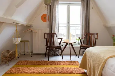 a bedroom with a bed and chairs and a window at Rembrandt Studio's in Amsterdam