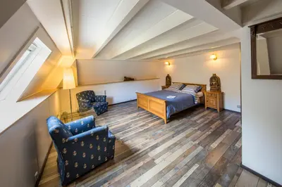 a bedroom with a bed and a couch and a chair at de zanderij in 's-Graveland