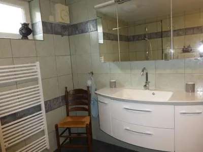 a bathroom with a sink and a mirror and a chair at de zanderij in 's-Graveland