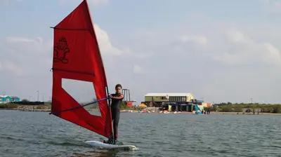 a man on a surfboard with a sail on the water at Room With A Few in Amsterdam