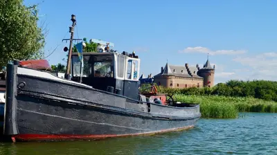 a boat in the water with a castle in the background at Room With A Few in Amsterdam