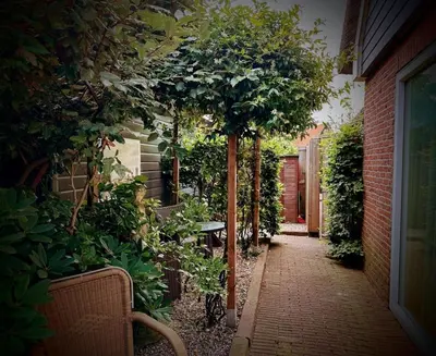 a garden with a tree and a table and chairs at Beach Holiday Appartements in Dirkshorn