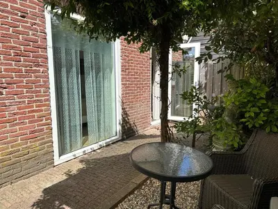 a table and a chair in front of a window at Beach Holiday Appartements in Dirkshorn