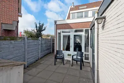 a screened in patio with two chairs and a table at Wijkiki Surf House in Wijk aan Zee