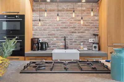 a kitchen with a stove and a brick wall at Wijkiki Surf House in Wijk aan Zee