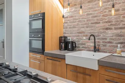 a kitchen with a sink and a brick wall at Wijkiki Surf House in Wijk aan Zee