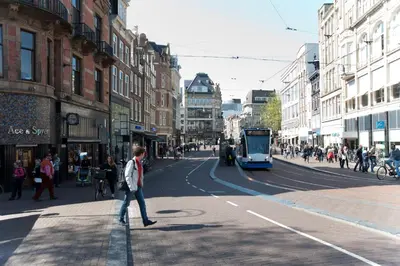 a man walking down a city street with a tram at Residence Flower Market in Amsterdam