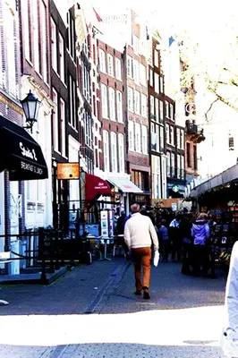 a man walking down a city street with buildings at Top Of The City in Amsterdam