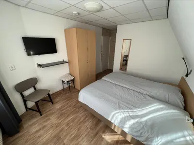 a bedroom with a bed and a tv and a chair at Appartement 5 in Katwijk aan Zee