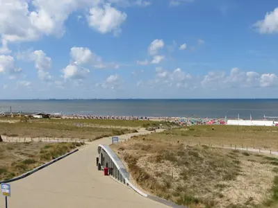 a walkway to the beach with the ocean in the background at Appartement 5 in Katwijk aan Zee