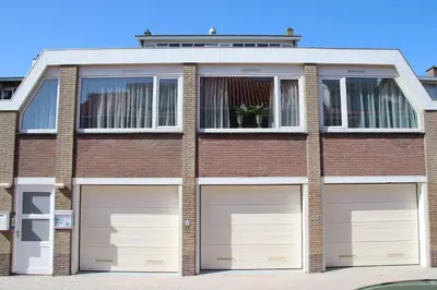 a brick house with two garage doors in front of it at Appartement 5 in Katwijk aan Zee