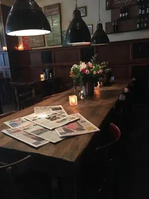 a wooden table with newspapers and magazines on it at Beach Hotel Katwijk in Katwijk