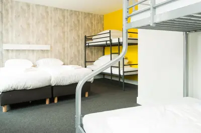 a room with three bunk beds and a staircase at Beach Hotel Katwijk in Katwijk