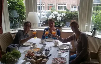 three people sitting at a table with glasses of orange juice at Bed & Breakfast Frans Hals Haarlem in Haarlem