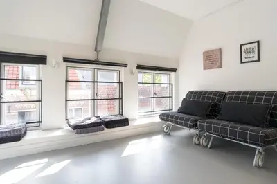 a living room with a couch and some windows at Tweede Laurierdwarsstraat Apartment in Amsterdam