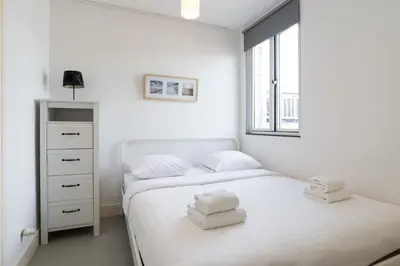 a white bedroom with two beds and a window at Tweede Laurierdwarsstraat Apartment in Amsterdam