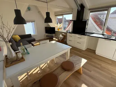 a kitchen and living room with a white table at BeachVibes in Egmond aan Zee