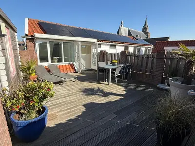 a patio with a table and chairs on a deck at BeachVibes in Egmond aan Zee