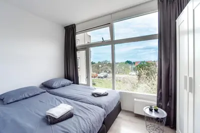 a bedroom with a bed and a large window at Papillon flat in Zandvoort