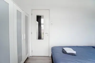 a bedroom with a bed and a door with a mirror at Papillon flat in Zandvoort