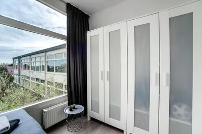 a bedroom with white cabinets and a large window at Papillon flat in Zandvoort