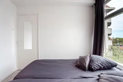 a bedroom with a bed with a large window at Papillon flat in Zandvoort